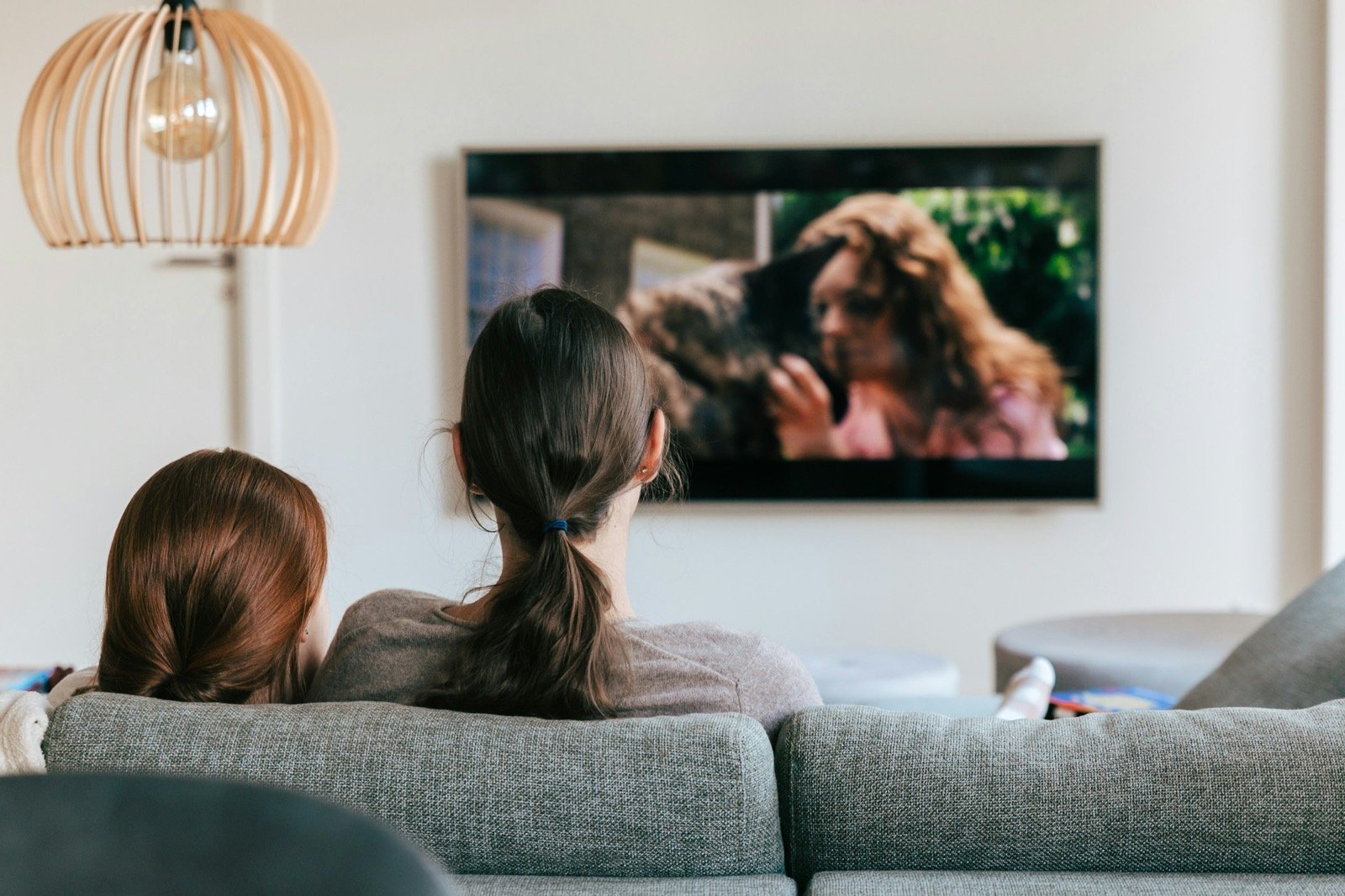 Two people on a sofa watching a film on a wall-mounted TV