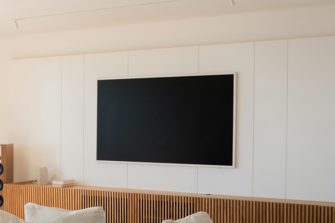 A bright living room with a wall-mounted TV switched on by SmartCtrl